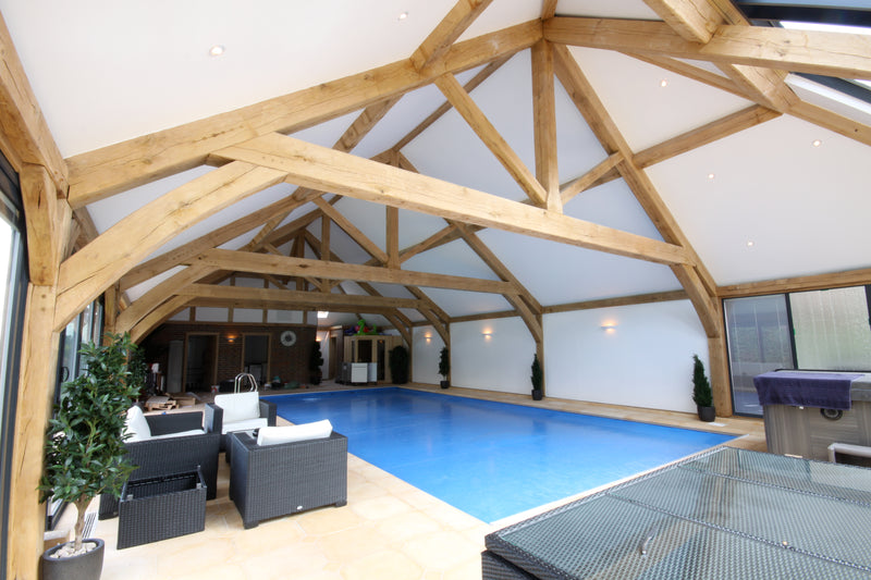 Indoor swimming pool with wooden beams and modern furniture