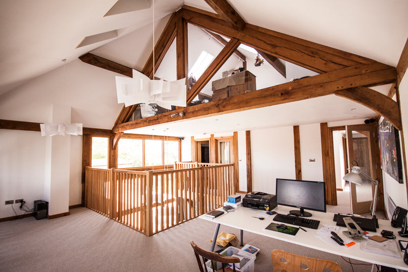 Modern office with wooden beams, desk, and computer setup.